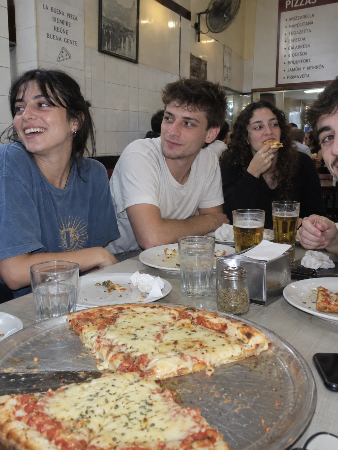 Amigos compartiendo pizza y una charla en una pizzería de barrio